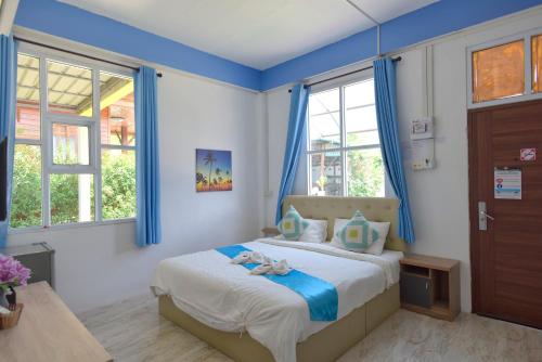 a bedroom with a bed with blue walls and windows at Chomduen Phu Kao Resort in Non Sang