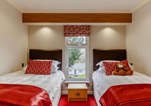 um quarto com duas camas com um urso de peluche sentado nelas em Meadow Lodge - Cornwall em Cardinham