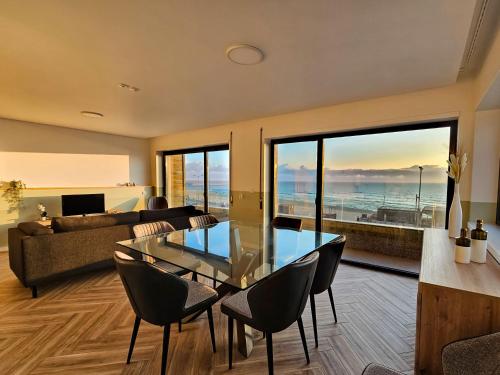uma sala de estar com uma mesa de vidro e cadeiras em CUSTÓDIO SEA HOME na Praia de Mira