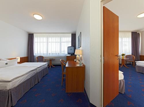a hotel room with two beds and a desk at Kim Hotel Dresden in Dresden