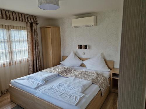 sypialnia z łóżkiem z białą pościelą i poduszkami w obiekcie Csalánosi Vendégház w mieście Kecskemét