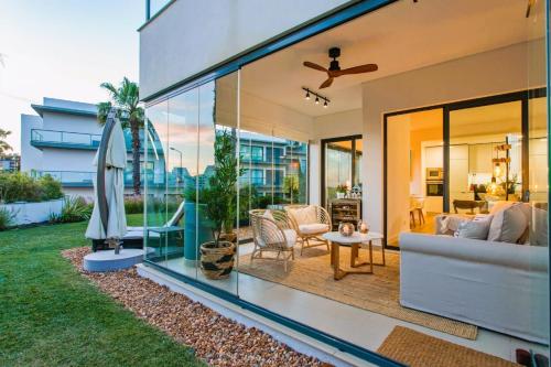 a house with glass walls and a patio at Cavalo Preto Beach Residence with Garden & Pool in Quarteira