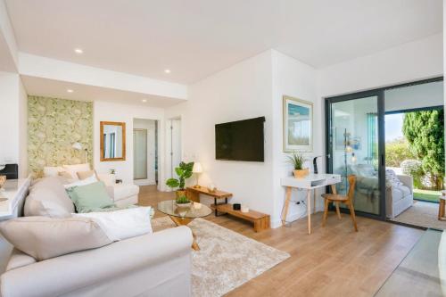 a living room with white furniture and a tv at Cavalo Preto Beach Residence with Garden & Pool in Quarteira