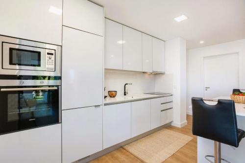 a kitchen with white cabinets and a sink and a microwave at Cavalo Preto Beach Residence with Garden & Pool in Quarteira