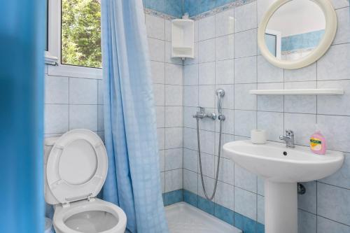 a bathroom with a toilet and a sink and a mirror at Miranda Resort in Nikiana