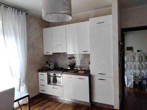 a kitchen with white cabinets and a stove top oven at Alba Langhe Apartment in Alba