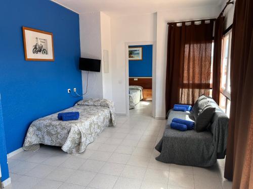 a bedroom with blue walls and a couch and a bed at Apartaments Monjardí in Lloret de Mar