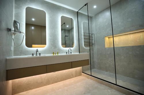 a bathroom with a sink and two mirrors at Amsterdam Hotel Aktobe in Aktobe