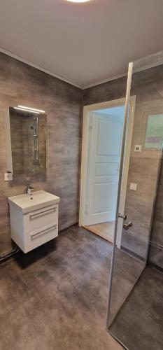 baño con lavabo, espejo y puerta en Nygård Cabins - brandnew holiday home with 3 bedrooms en Sunne