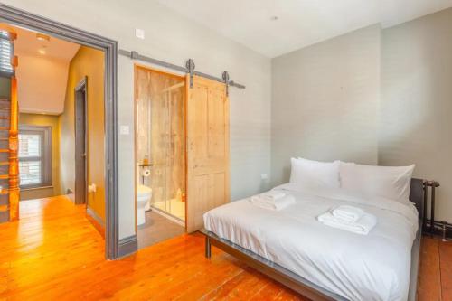 a bedroom with a large white bed and a bathroom at Inviting 4BD with Private Patio - Bethnal Green in London