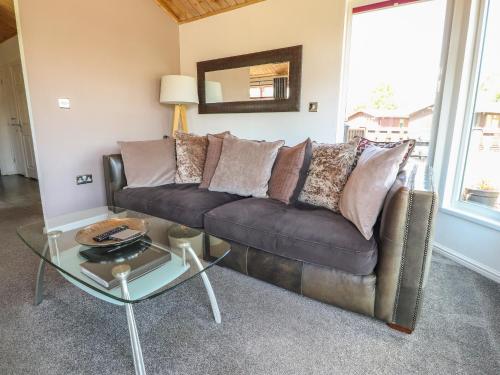 a living room with a brown couch and a glass table at Doormouse Lodge in Carnforth