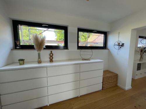 a white dresser in a room with two windows at Mit gutem Gefühl ferienwohnen 