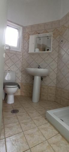La salle de bains est pourvue d'un lavabo, de toilettes et d'une baignoire. dans l'établissement marianthi's apartment, à Plataria