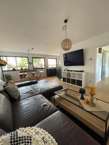 a living room with a leather couch and a flat screen tv at Mit gutem Gefühl ferienwohnen in Ballingshausen