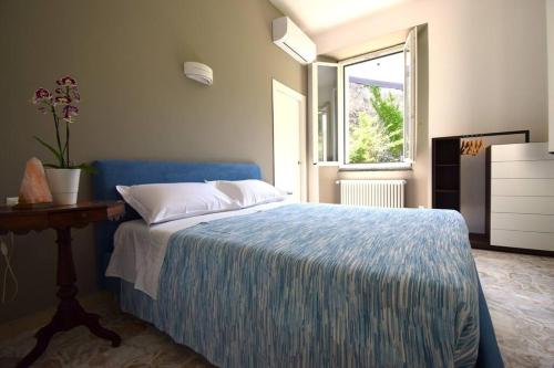 Schlafzimmer mit einem blauen Bett, einem Tisch und einem Fenster in der Unterkunft Appartamento Belle Epoque vista lago in Onno