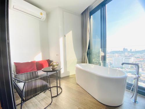a bathroom with a tub and a chair and a window at Edge Central Pattaya Vip Condo in Pattaya Central
