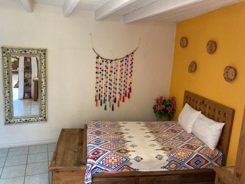 a bedroom with a bed with a colorful quilt on the wall at Cálida habitación a 10 min de Santo Domingo in Oaxaca City