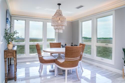 a dining room with a table and chairs and windows at 2105 Bay Pointe Villa in Seabrook Island