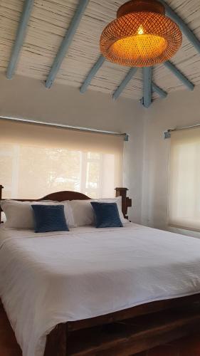 um quarto com uma grande cama branca e um lustre em Casa Coclín - Paraíso Campestre em Sáchica