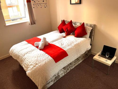 - un lit avec des draps rouges et blancs et des oreillers rouges dans l'établissement Well connected Birmingham City centre apartment with secure parking, à Birmingham