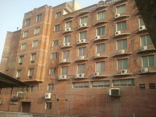a large red brick building with air conditioners at Carlton Tower Hotel Lahore in Lahore