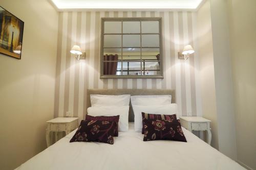 una camera con un letto bianco con due cuscini di Saint Germain Elegant ChicSuites a Parigi