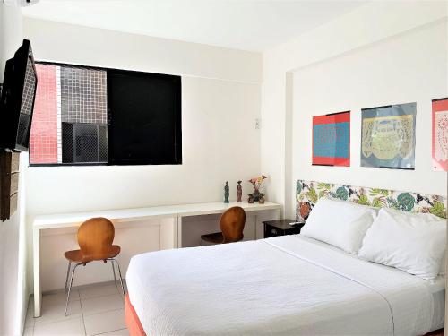 een slaapkamer met een bed, een bureau en een televisie bij Edifício Setai Apto 413 ER Hospedagens in Maceió