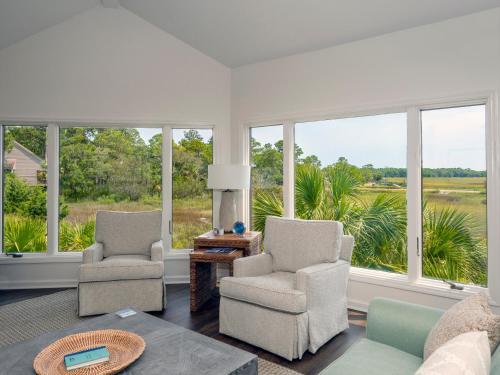a living room with two chairs and a table and windows at 1515 Deer Pointe Villa in Seabrook Island