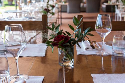 a wooden table with wine glasses and a vase of flowers at Locanda Poggioleone in Castiglione del Lago