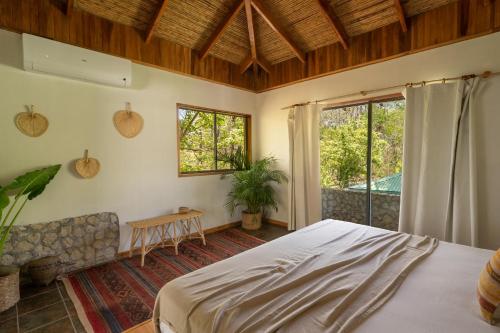 a bedroom with a bed and a couch and windows at Dream Surf House Avellana in Playa Avellana