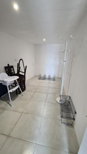 une pièce blanche avec un sol blanc et une table et des chaises dans l'établissement La Maison bleue des Mathes, aux Mathes