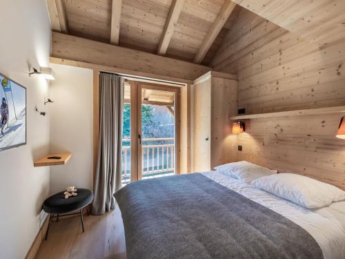 ein Schlafzimmer mit großem Bett und Balkon in der Unterkunft Chalet moderne à Méribel avec 5 chambres, sauna et accès rapide aux pistes - FR-1-566-45 in Les Allues