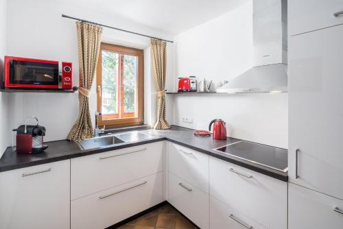 a kitchen with white cabinets and a sink and a window at Sunneschlössli Tannheimer Tal in Nesselwängle
