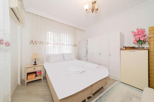 a white bedroom with a bed and a table at Apartment with Panoramic City View in Kepez in Antalya