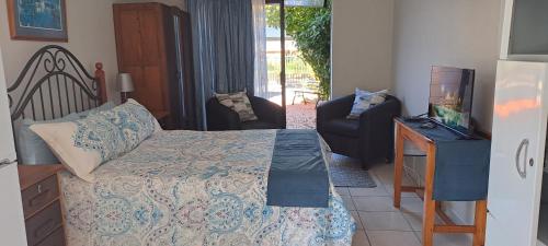 1 dormitorio con 1 cama, TV y silla en The Cottage Unit, en Bloemfontein