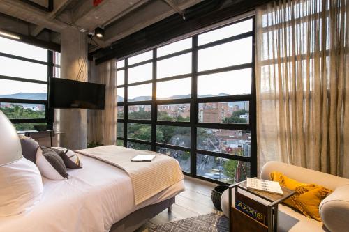 a bedroom with a bed and a large window at Factory Lofts Hotel in Medellín
