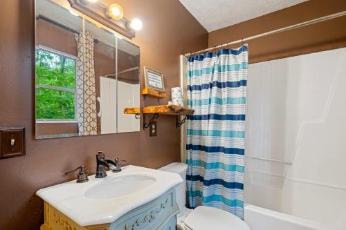 a bathroom with a sink and a toilet and a mirror at Artisan Hideaway in Helen