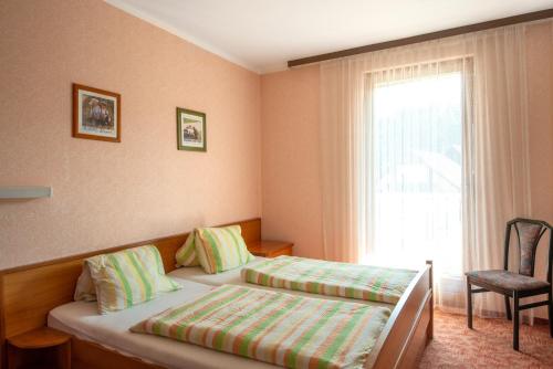 um quarto com 2 camas, uma janela e uma cadeira em CHECK in ECK MOTEL em Sankt Kanzian