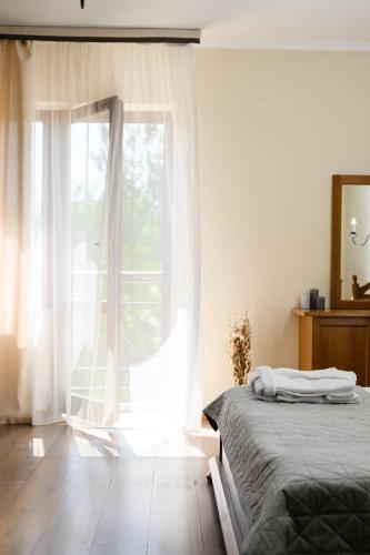 a bedroom with a bed and a large window at Bogolvar Retreat Resort in Antonovka