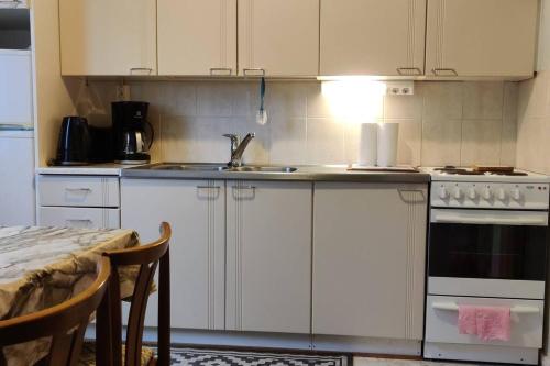 a kitchen with white cabinets and a sink and a table at Cozy easy-to-stay 2room apartment 1km from Rauma centre in Rauma