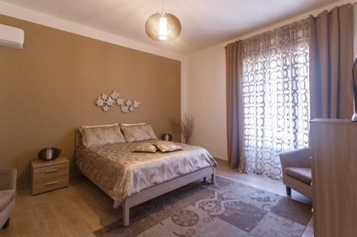 a bedroom with a bed and a large window at Montellinos Suite Tortora in SantʼAntìoco