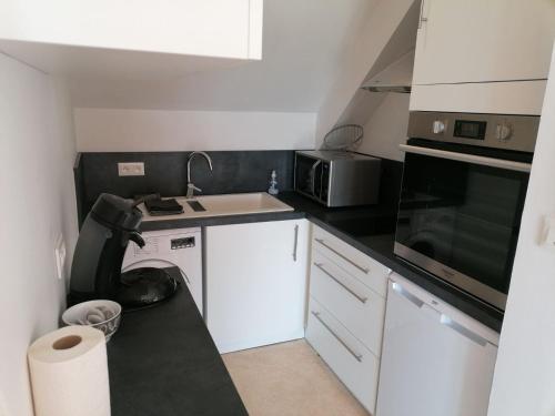 eine kleine Küche mit einer Spüle und einer Mikrowelle in der Unterkunft Studio avec vue sur la Baie in Avranches