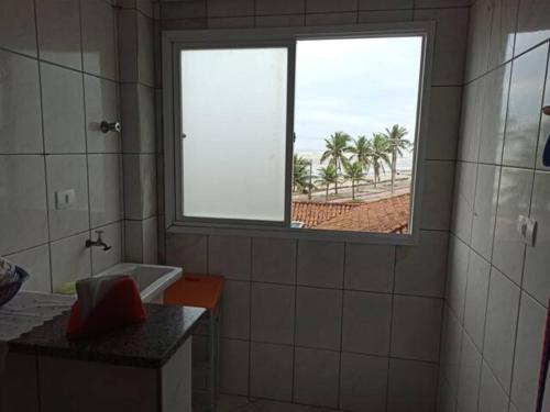 a bathroom with a window and a sink and palm trees at Ótimo Apartamento Frente ao Mar em Mongaguá in Mongaguá