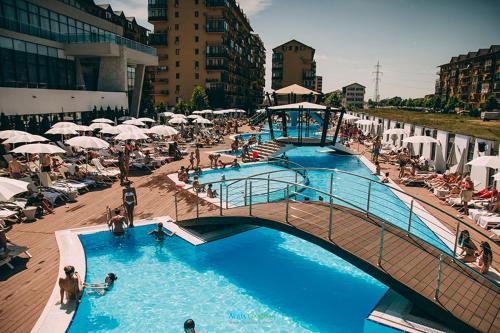 a large swimming pool with people and umbrellas at Fun Apartament Militari Residence in Roşu