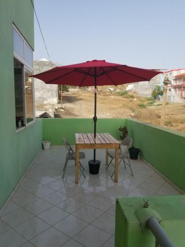a table with an umbrella on a patio at chez albino guest house in São Filipe