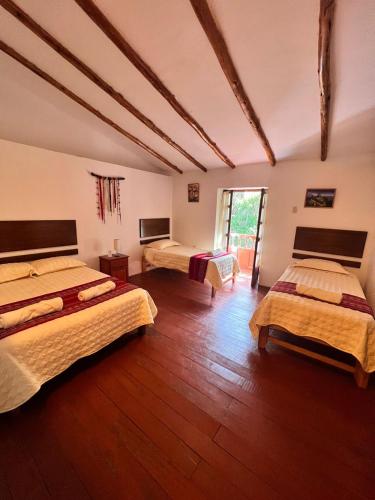 a large room with three beds in it at Posada Del Valle Lodge in Urubamba