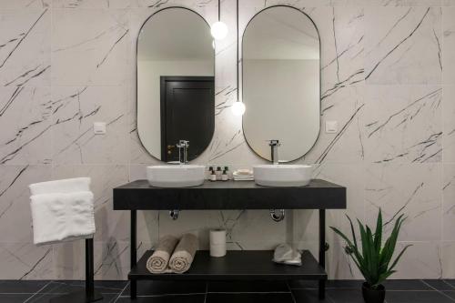 a bathroom with two sinks and two mirrors at Soho Suites in Bar