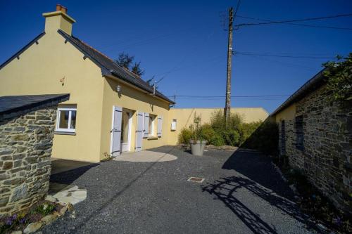 a yellow house with a driveway next to a building at Gîte Des Huttes in Bain-de-Bretagne