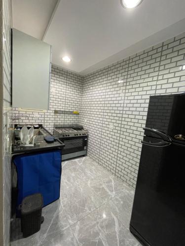 a kitchen with a black refrigerator and tile walls at Luxury , apartment for business trips or student in Cairo