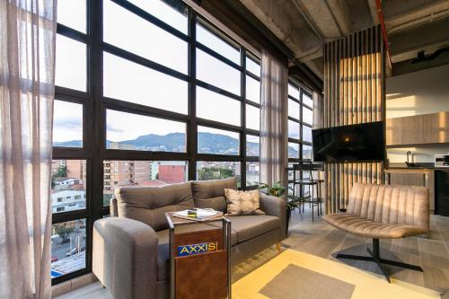 a living room with a couch and large windows at Factory Lofts Hotel in Medellín